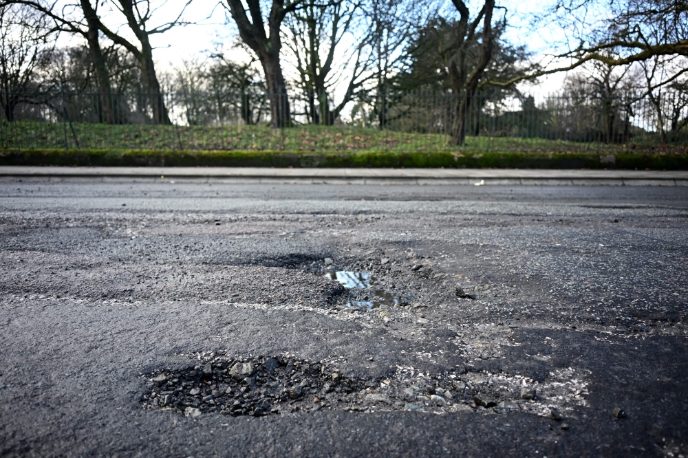 A car is driven past a pothole in a damaged road in Liverpool, north west England on January 30, 2024. The British government announced on March 24, 2025 that it would be releasing new funds to enable local authorities to repair the potholes that have plagued Britain's roads for years, and have become a symbol of the poor state of public infrastructure. — AFP pic