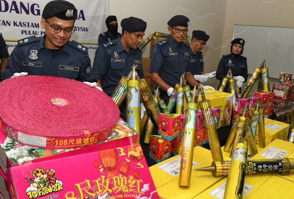 Officers from the Royal Malaysian Customs Department in Penang examines various types of firecrackers seized. — Bernama pic