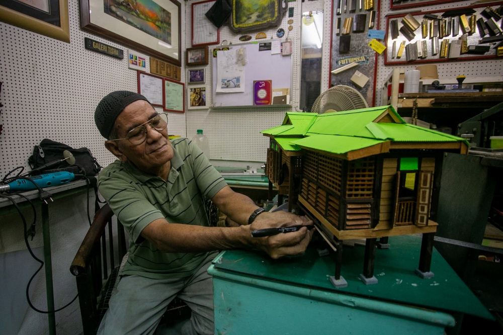 Woodcraft artisan Saari Ali, 70, busy completing an order for traditional house replicas at his gallery in the Urban Transformation Centre (UTC) building in Ipoh recently, March 25, 2025. — Bernama pic 