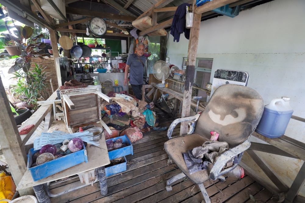 Flood victim Arip Aripin, 78, surveys his house at Kampung Pasir Tebrau, now dirty and covered in mud following the massive floods that hit Johor on March 19. — Bernama pic