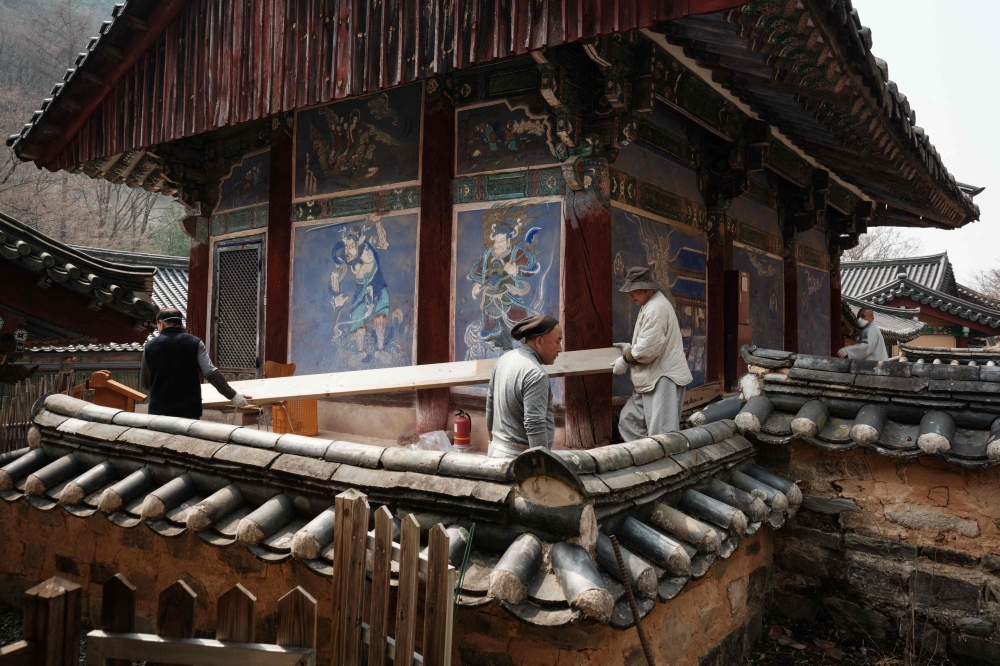 Buddhist monks remove flammable materials around the buildings during preparations for the possibility of a wildfire advancing towards Gounsa Temple in Uiseong on March 25, 2025. — AFP pic