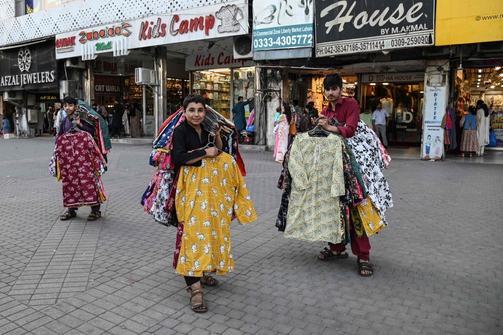 Street vendors selling women’s clothes wait for customers at the Liberty Market in Lahore March 21, 2025. — AFP pic