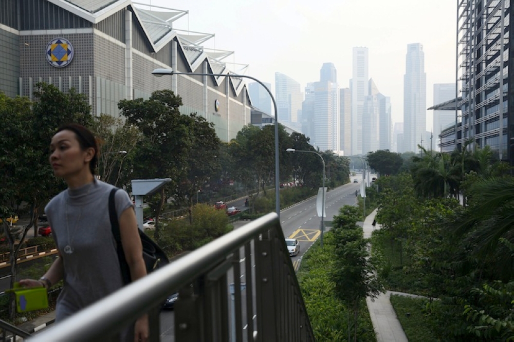 File photo of a woman taking a pedestrian bridge in the backdrop of the city skyline shrouded by haze in Singapore. At 9am, the country’s Pollutant Standards Index (PSI) readings ranged from 61 to 75, with the highest levels recorded in the central region. — Reuters file pic