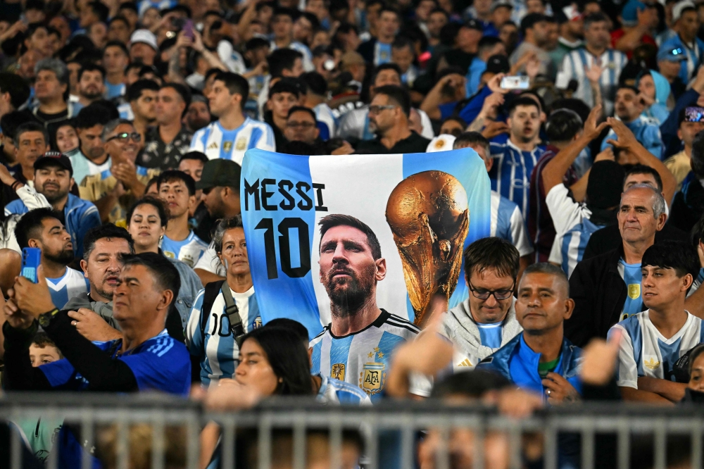 Fans of Argentina hold a flag with a picture of Lionel Messi before the start of the 2026 Fifa World Cup South American qualifiers match between Argentina and Brazil at the Mas Monumental stadium in Buenos Aires March 25, 2025. — AFP pic