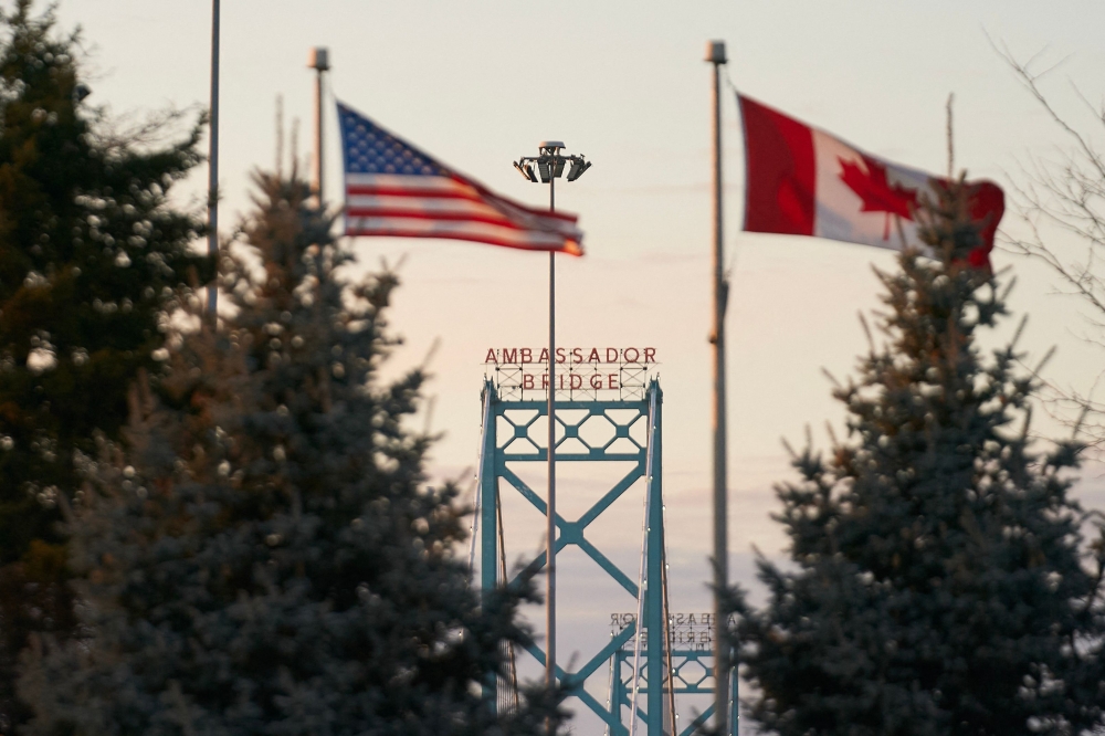 Canadian and American flags fly on the Canadian side of the Ambassador Bridge in Windsor, Ontario March 8, 2025. The US was the top destination for Canadian tourists, with 20.4 million visits reported last year by the US Travel Association, pumping some US$20.5 billion (RM90.7 billion) into the American economy and supporting 140,000 jobs. But that number is expected to plummet this year as Canadians cancel their travel plans. — AFP pic