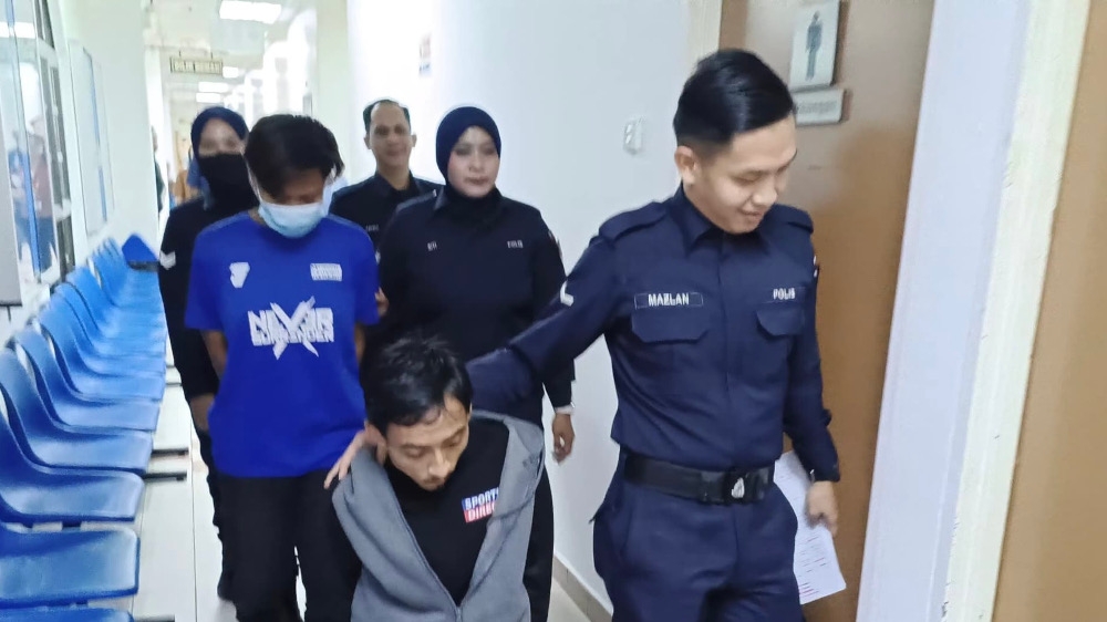 Mohamad Hafizwan Ayob (front, left) being escorted by a policeman ar the Johor Baru Sessions Court, March 27, 2025. — Picture by Ben Tan