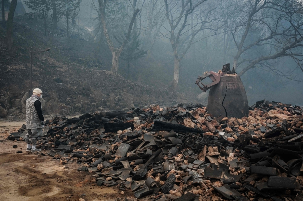 A monk looks at a cracked temple bell remaining after most of the buildings were burned to the ground in a wildfire at Gounsa Temple in Uiseong March 26, 2025. — AFP pic