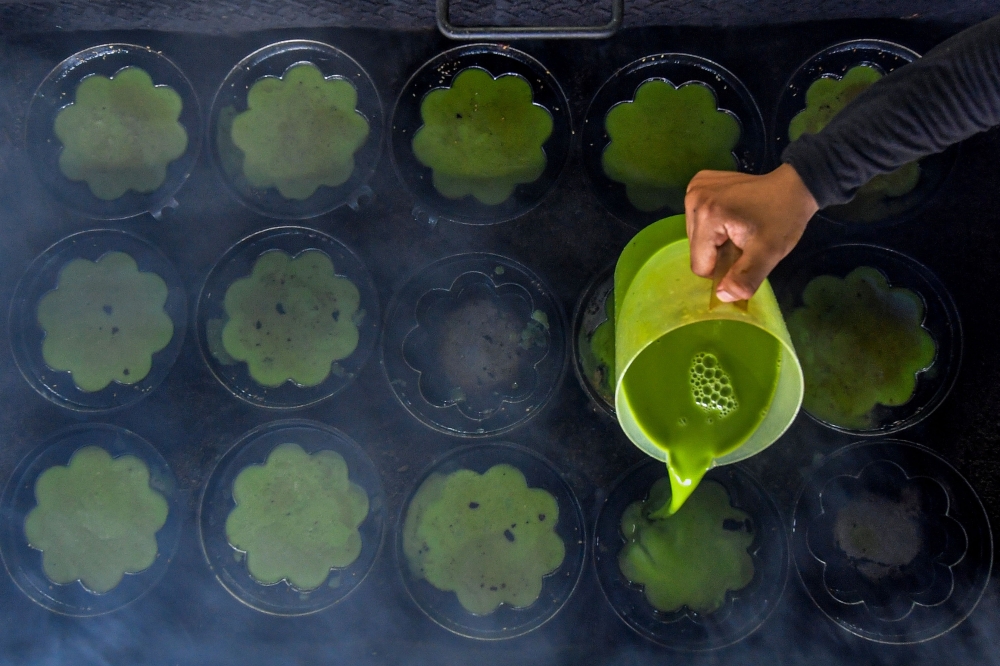 Ainur Latifa Mohd Zaidi pours tbatter into a special ‘kuih bakar’ mould at her father Mohd Zaidi Abdul Latib’s stall in Kampung Semin, Rembau March 28, 2025. — Bernama pic