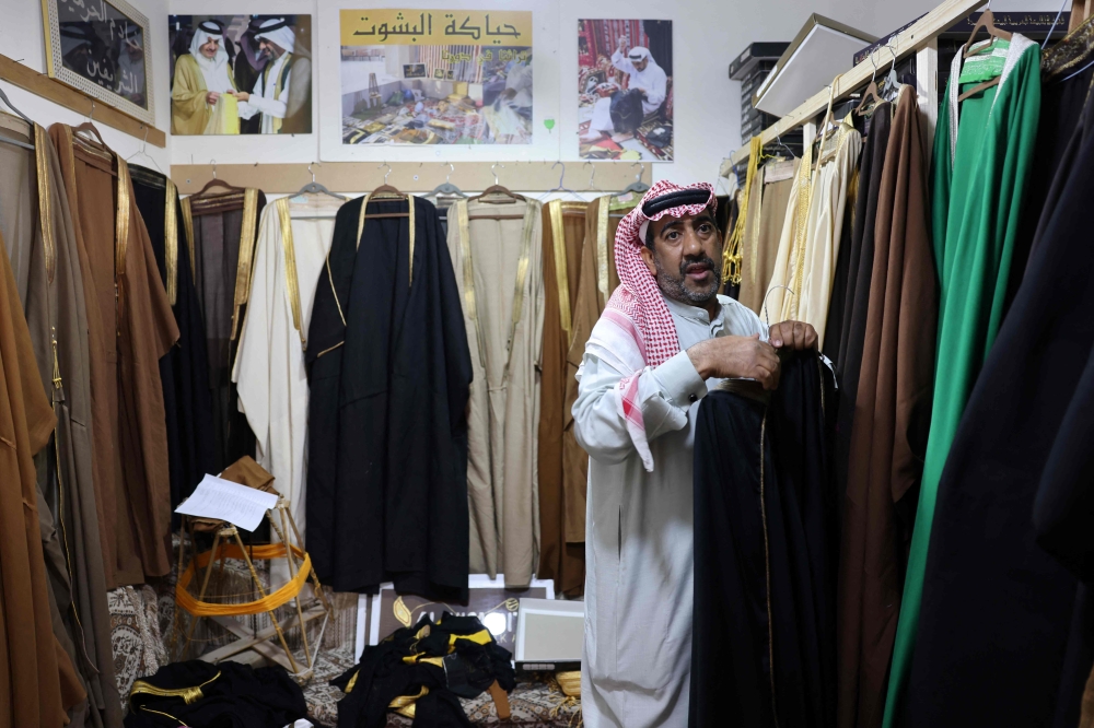 Saudi tailor Habib Mohammed arranges his production of bishts, ornate, hand-woven long cloak that for centuries have been a status symbol, worn by kings and princes. — AFP