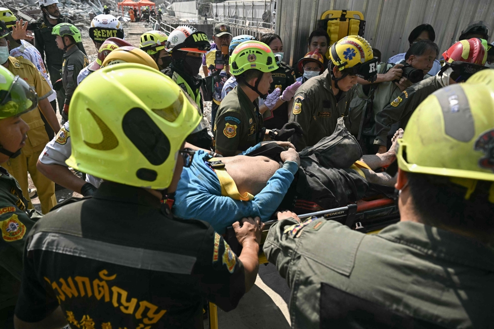 An injured man is rescued at a construction site where a building collapsed in Bangkok on March 28, 2025. — AFP pic