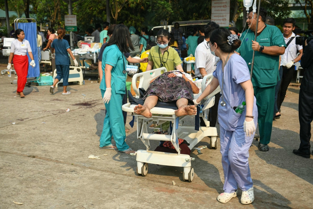 Medical workers transport an earthquake casualty in the compound of a hospital in Naypyidaw. — AFP pic