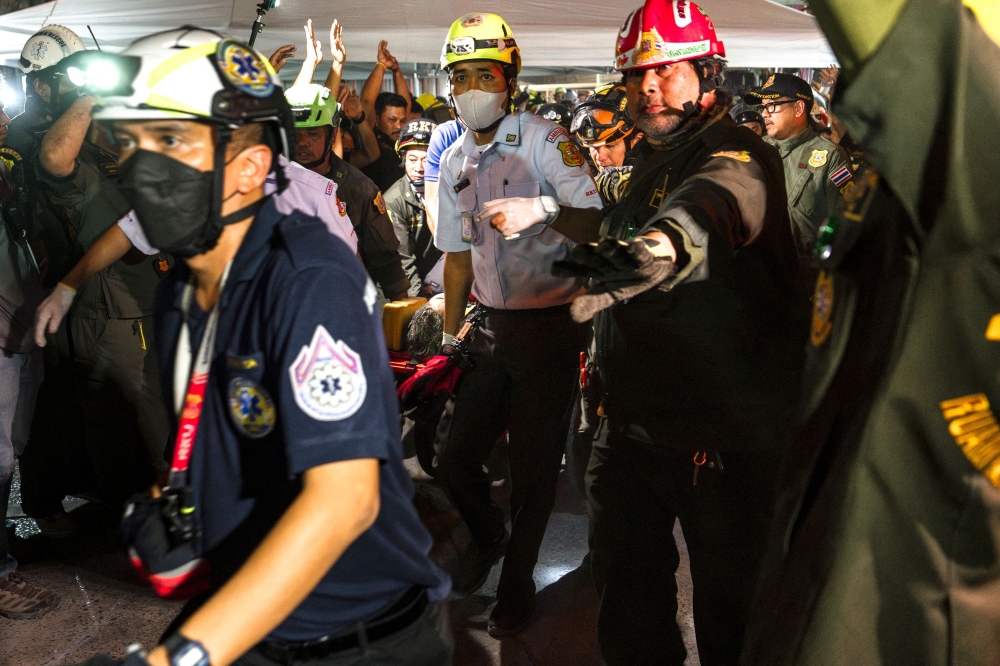 Rescue teams evacuate an injured man in a stretcher at a construction site where a building collapsed in Bangkok on March 28, 2025. — AFP pic