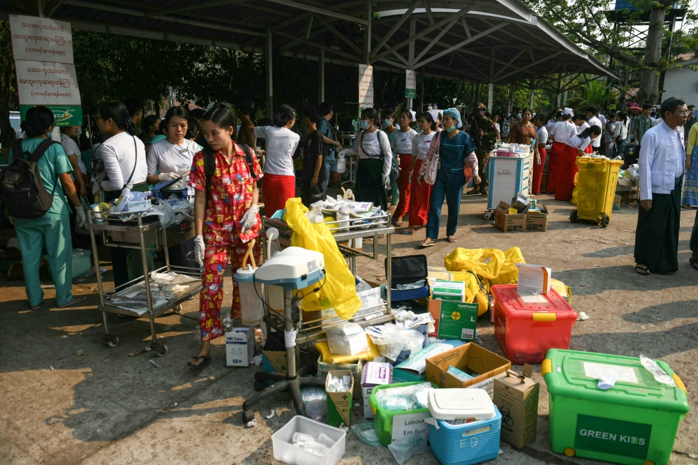 Medical workers and people walk past boxes of medical material placed in the compound of a hospital in Naypyidaw on March 28, 2025, after an earthquake in central Myanmar. — AFP pic