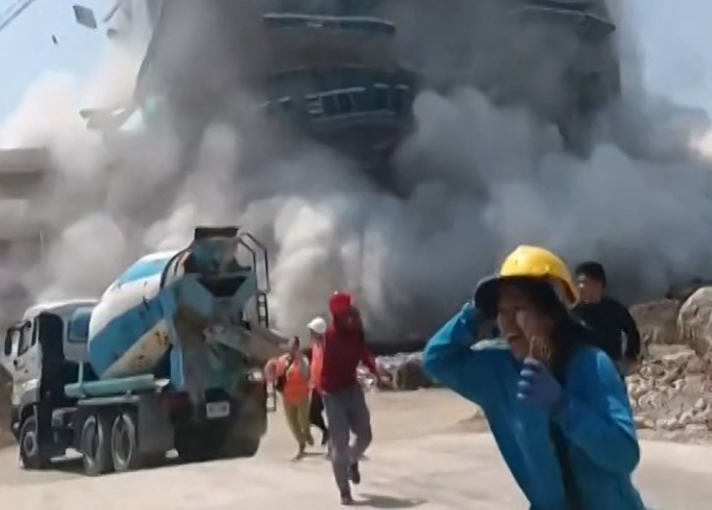 A frame grab shows workers running away from a building as it collapses at a construction site in Bangkok, following an earthquake. — AFP pc/ Courtesy of Facebook user Khon Su Cheevit Adeet Mai Suay Rok Na