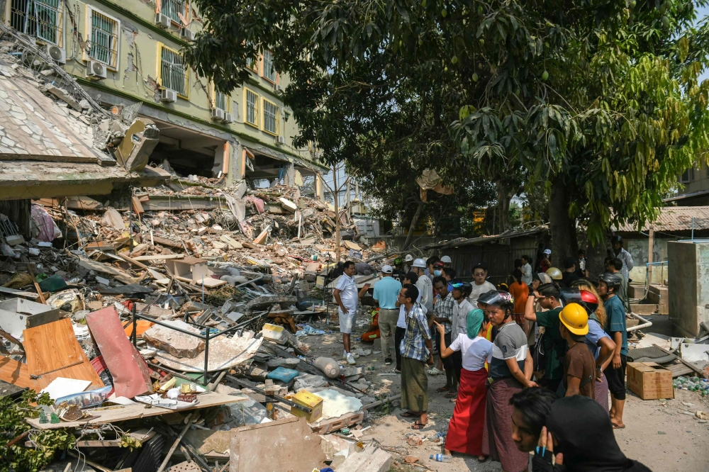 Rescue workers attempt to free residents trapped under the rubble of the destroyed Sky Villa Condominium development in Mandalay today. — AFP pic