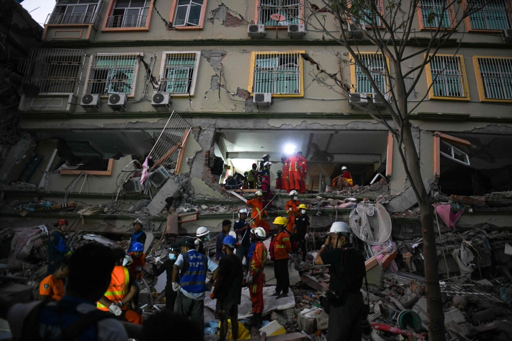 Rescue teams work to save residents trapped under the rubble of the destroyed Sky Villa Condominium development building in Mandalay yesterday. — AFP pic