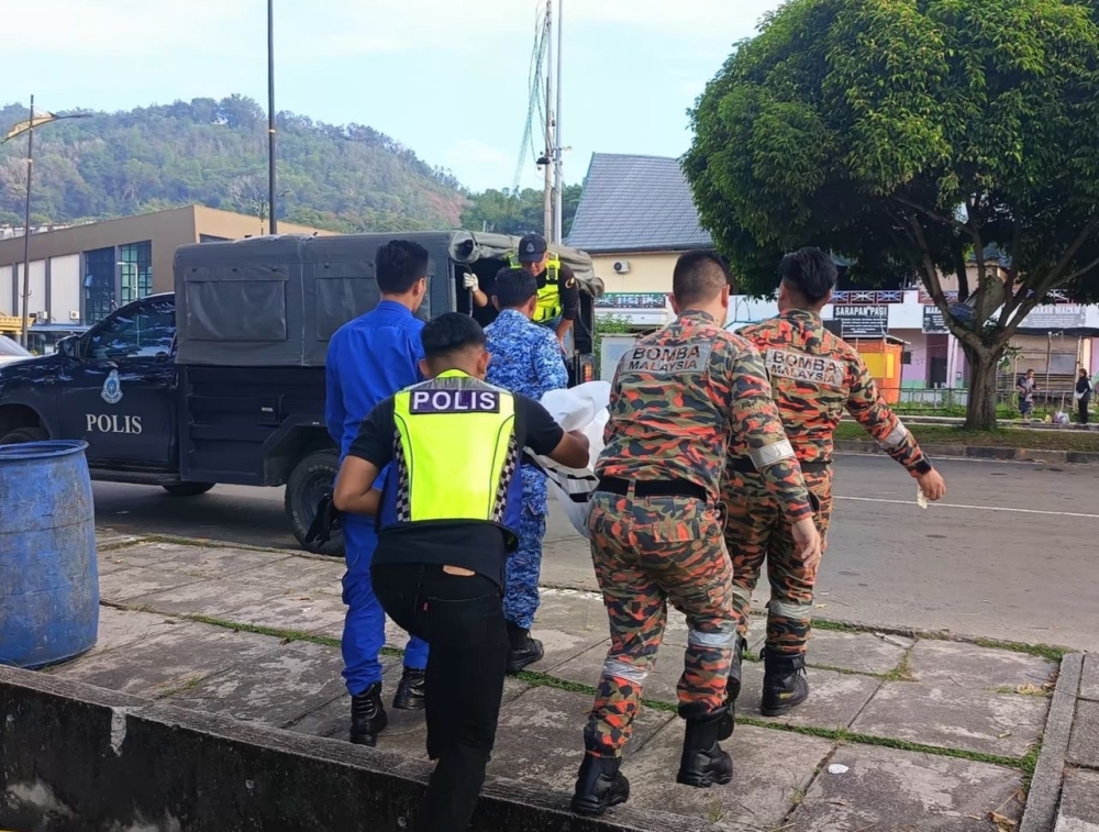 Authorities retrieving the body of the boy in Sandakan. — The Borneo Post pic