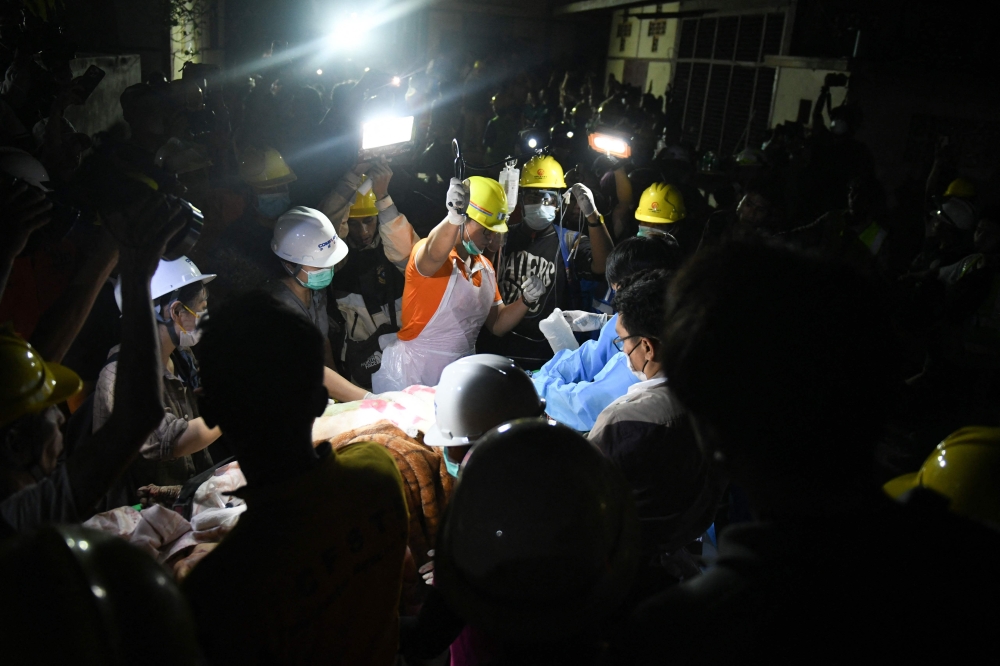 Doctors and medics teams treat a victim trapped under the rubble of the destroyed Sky Villa Condominium development in Mandalay yesterday. — AFP pic