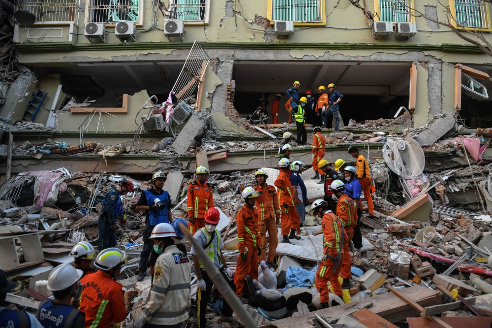 Rescue teams work to evacuate residents trapped under the rubble of the collapsed building 'Sky Villa Condominium development' in Mandalay on March 30. — AFP pic