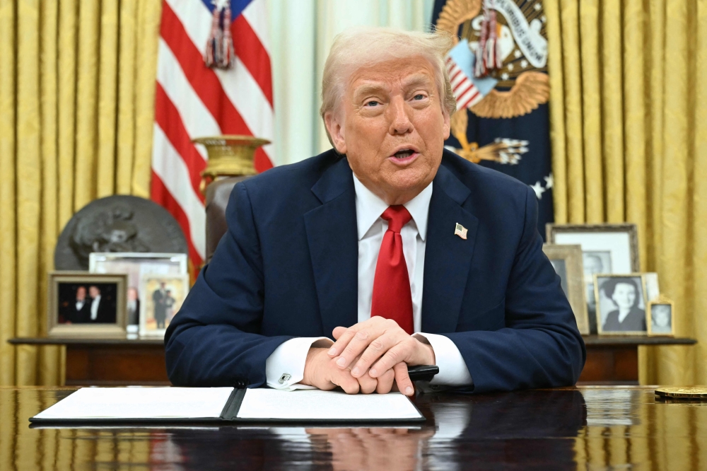 US President Donald Trump speaks as he signs an executive order in the Oval Office of the White House in Washington, DC yesterday. — AFP pic