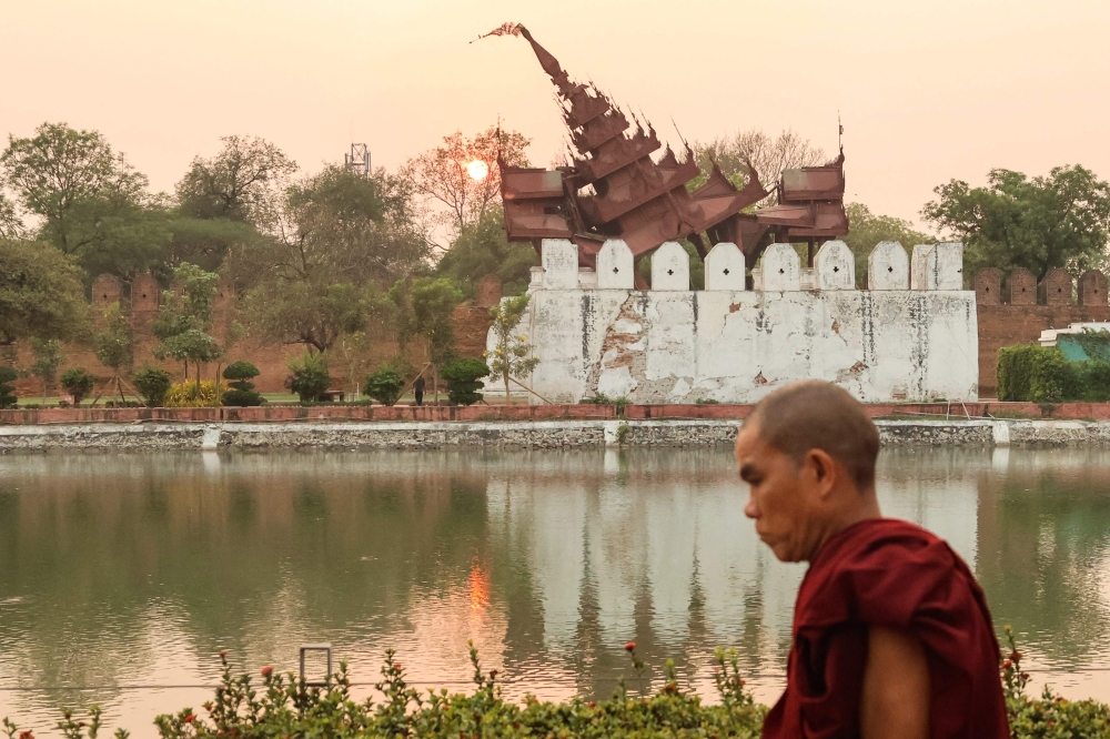 A Buddhist monk walks past the damaged Mandalay Palace during sunset in Mandalay on March 31, 2025, three days after the deadly Myanmar earthquake. — AFP pic