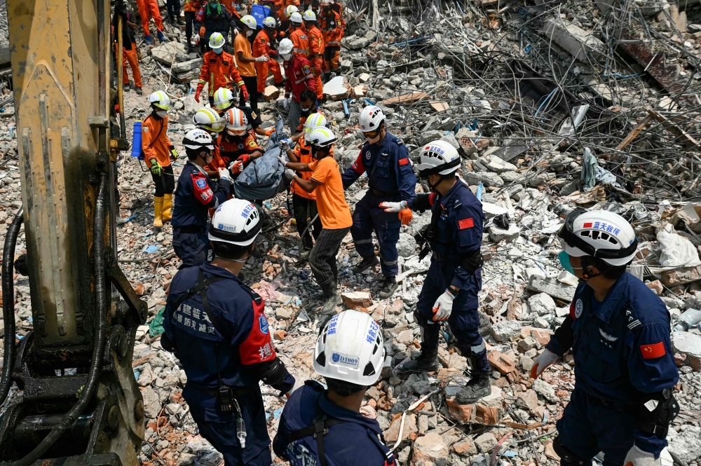 Myanmar and Chinese rescuers carry the body of a victim that was trapped under the rubble of the collapsed building 'Sky Villa Condominium development' in Mandalay on April 2, 2025, five days after a major earthquake struck central Myanmar. — AFP pic