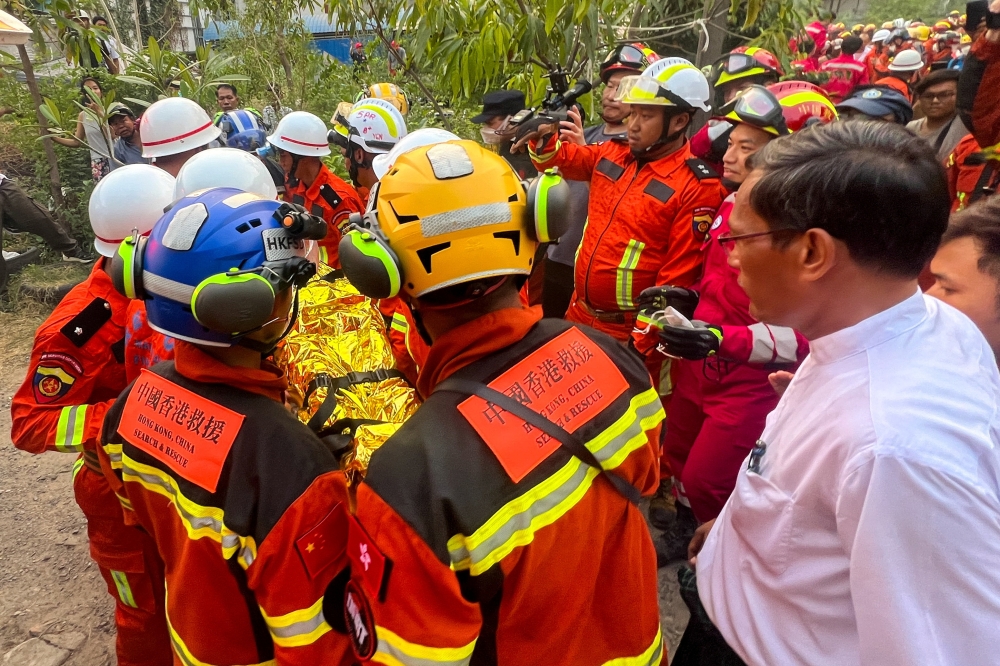 Chinese rescue workers carry a survivor trapped inside the Golden Country Hotel following a strong earthquake in Mandalay, Myanmar, April 2, 2025. — Reuters pic  