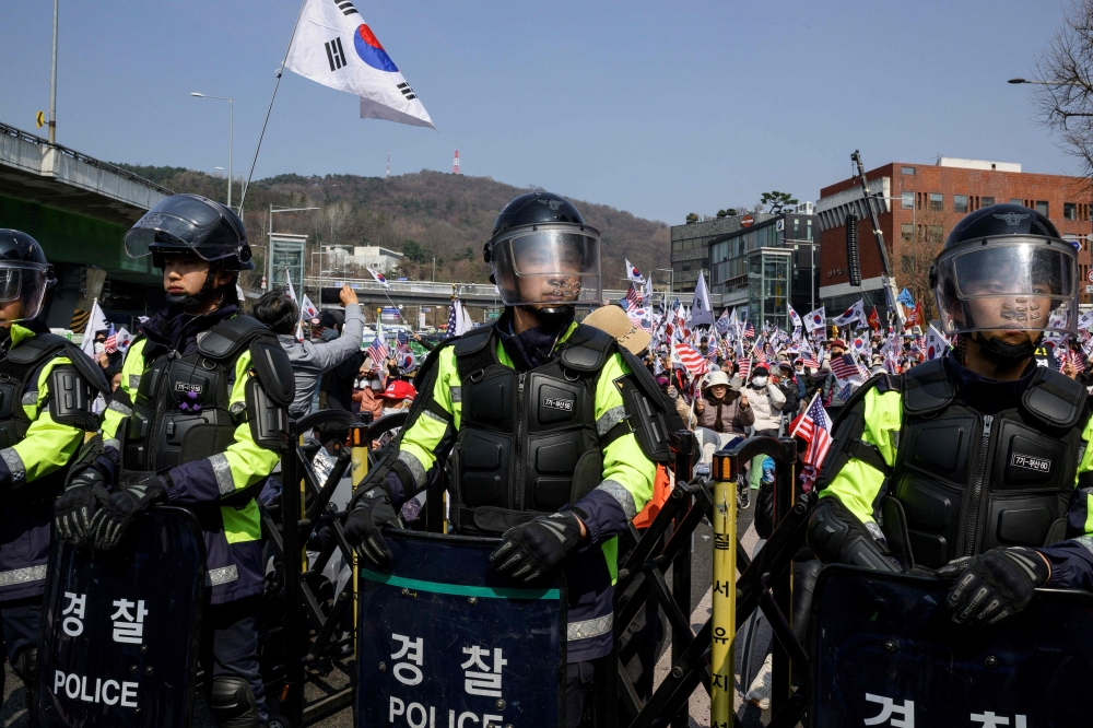Riot police stand guard in front of supporters of South Korea president Yoon Suk-yeol waiting for the Constitutional Court verdict on his impeachment outside the presidential residence in Seoul April 4, 2025. — AFP pic