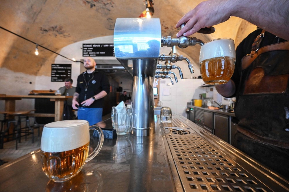 A bartender draws ‘Pilsner Urquell’ beer in the ‘U Rarasku’ pub in Prague, Czech Republic, on March 19, 2025. — AFP pic