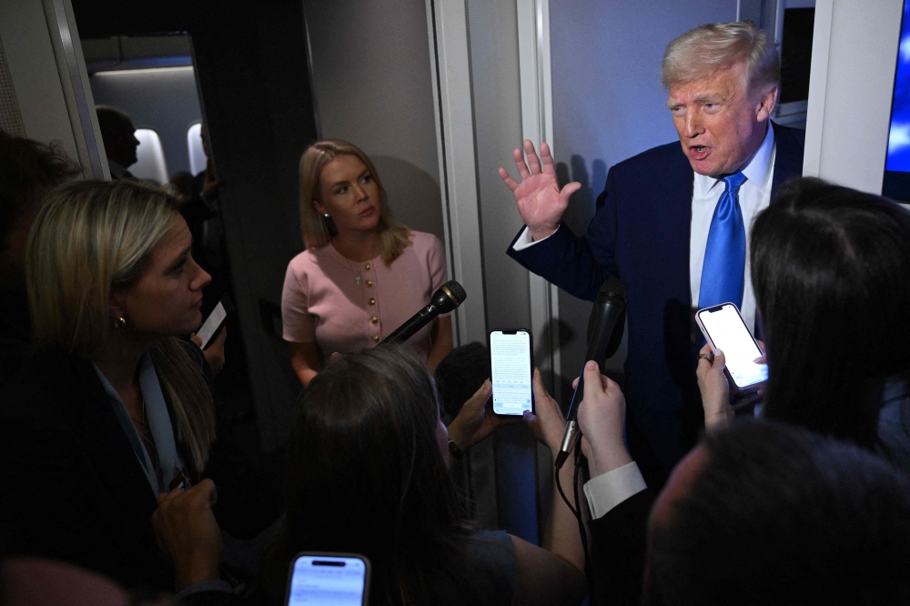 US President Donald Trump speaks to reporters while in flight on Air Force One, en route to Joint Base Andrews yesterday. — AFP pic