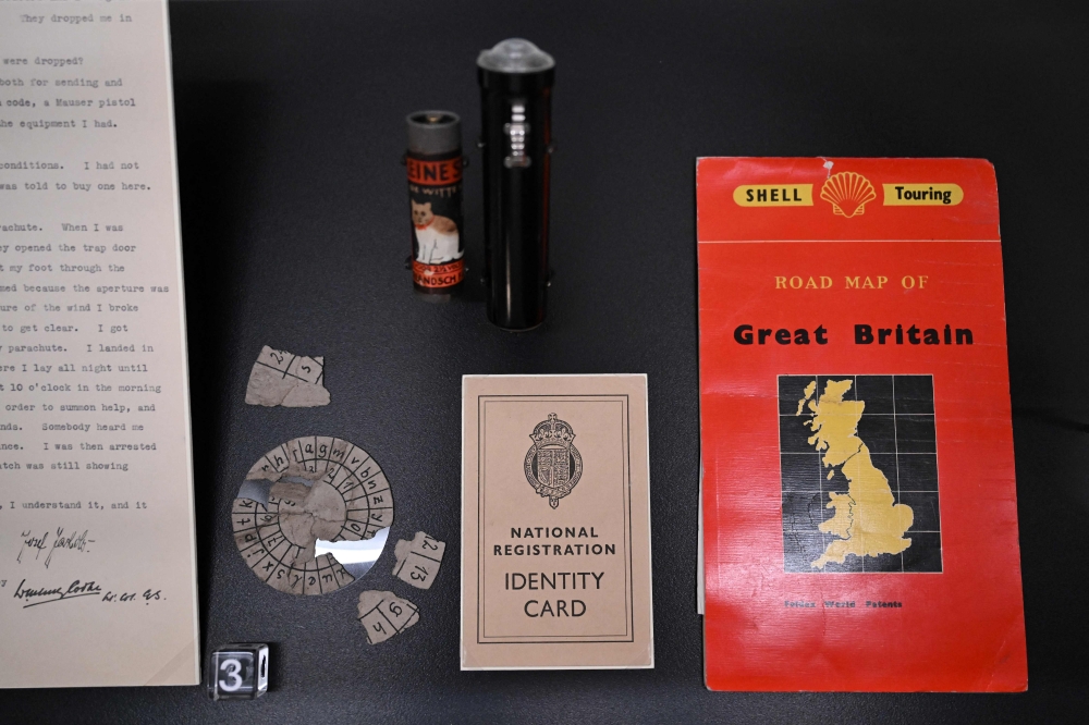A photograph taken on April 3, 2025 shows Josef Jakobs’ signed statement, torn up code wheel, torch and batteries, fake identity card and road map of Great Britain, displayed at the ‘MI5: Official Secrets’ exhibition at the National Archives in west London. — AFP pic