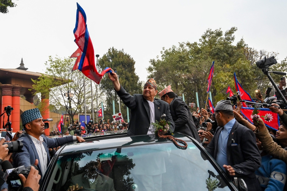 Nepal's former King Gyanendra Bir Bikram Shah Dev waves as he arrives at Tribhuwan International Airport in Kathmandu March 9. — AFP