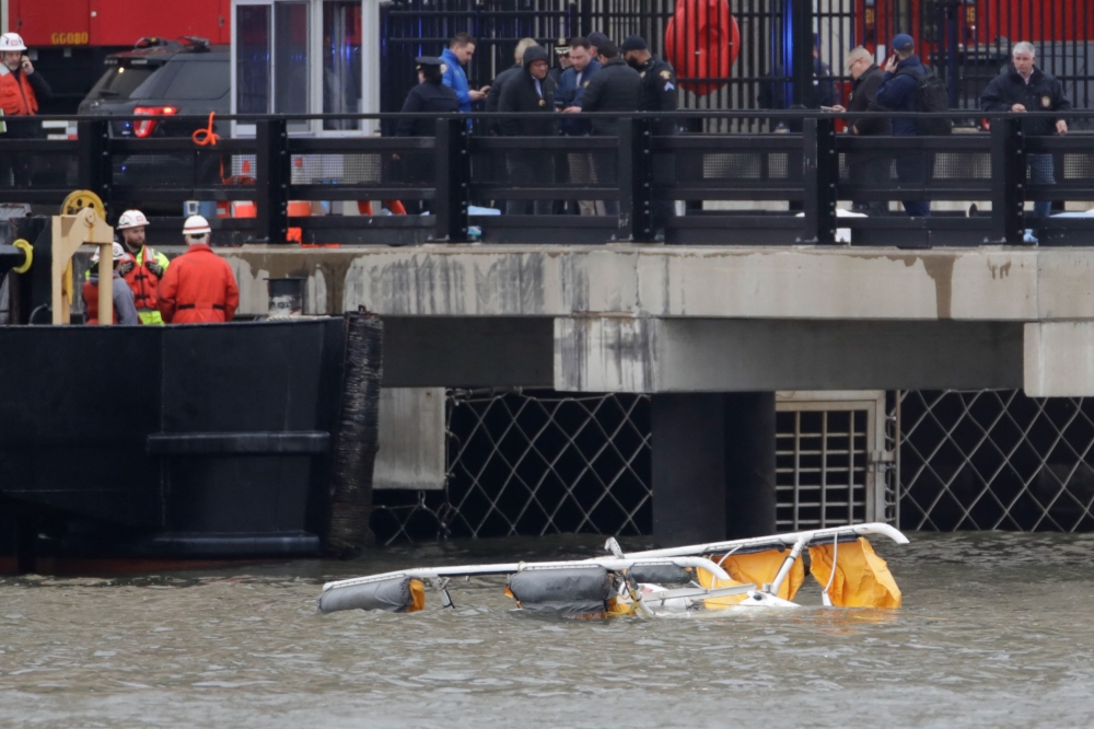 First responders are seen near the landing skids of a helicopter after it crashed into the Hudson River, in Newport, New Jersey, April 10, 2025. — AFP pic 
