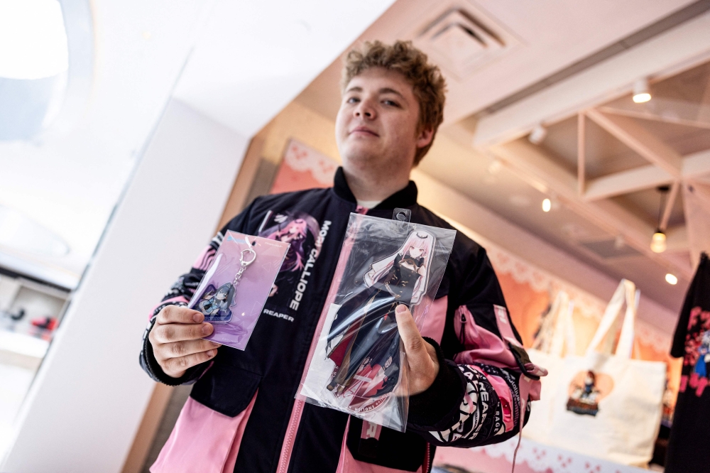 A Vtuber fan shows memorabilia he purchased at a Hololive pop-up store at the Beverly Center shopping mall in Los Angeles, California, on February 27, 2025. — AFP pic