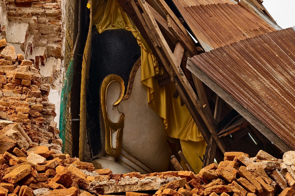 A damaged Buddha statue is surrounded by the debris of a collapsed building in Inn Wa on the outskirts of Mandalay on April 6, 2025, following the devastating March 28 earthquake. — AFP pic
