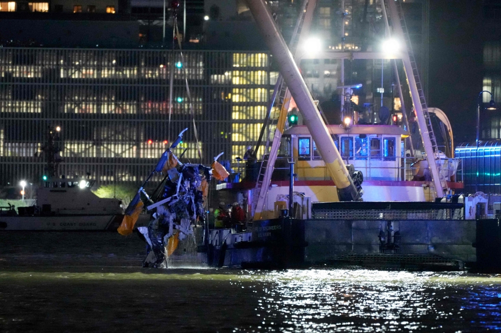 The wreckage of a helicopter is removed from the water after crashing into the Hudson River, in the Newport neighborhood of Jersey City. — AFP pic