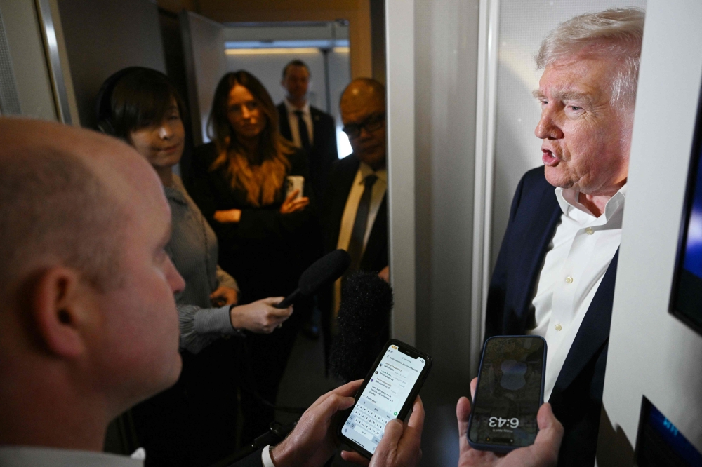 US President Donald Trump speaking to reporters while in flight on Air Force One, en route to Palm Beach International Airport. — AFP pic