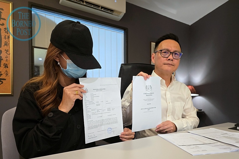 Bong (left) shows a copy of her police report while Foo shows a copy of the Computer Crimes Act 1997. — The Borneo Post pic