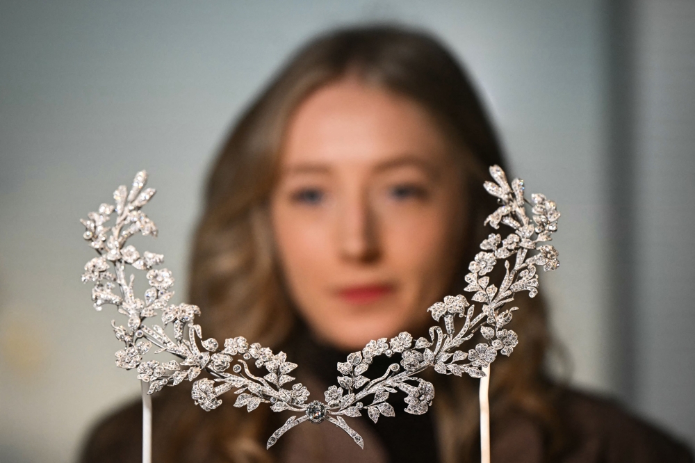 A visitor looks at the Lily Stomacher Brooch dated from 1906 and owned by US industrialist heiress and congresswoman Mary Scott Townsend during a photocall for the forthcoming Cartier exhibition at the V&A (Victoria and Albert) museum in London, on April 9, 2025. — AFP pic
