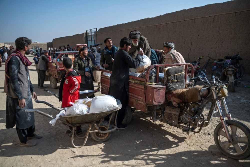 Afghan men load food packets on a vehicle that were distributed as an aid by the World Food Programme (WFP) organisation at Nawabad Kako Sahib area in Baraki Barak district of Logar Province on January 7, 2024. — AFP pic