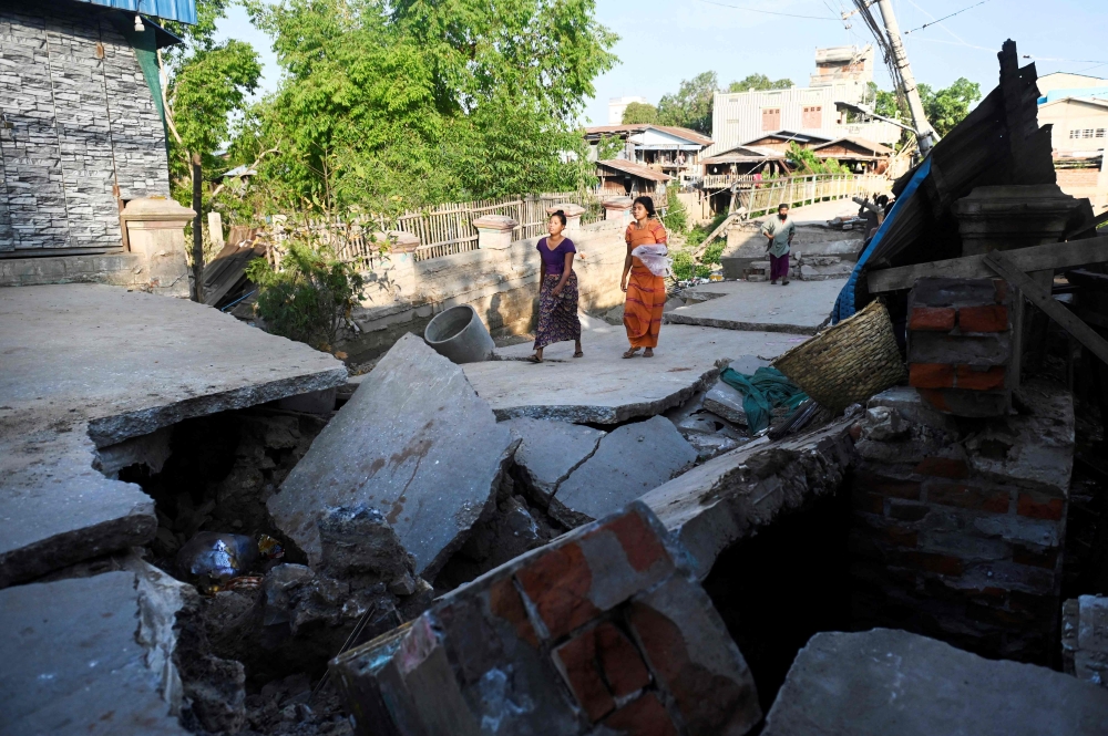 People walk on a damaged bridge in Mandalay on April 12, 2025, following the devastating March 28 earthquake. — AFP pic