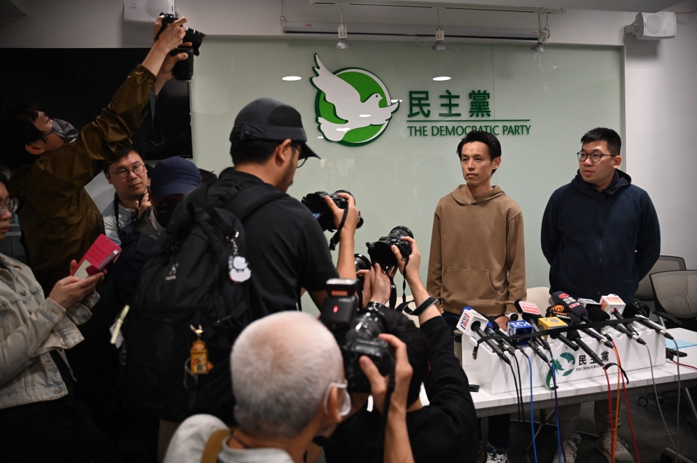 Lo Kin-hei (second right), chairman of Hong Kong's Democratic Party (DP), and vice-chairman Mok Kin-shing (right) attend a press conference at the party's headquarters in Hong Kong on April 13, 2025, after the DP's members' meeting to discuss the future of the party. — AFP pic