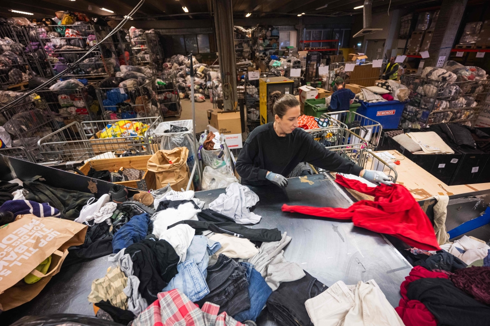 A worker sorts incoming clothing items at Artikel2’s sorting centre in Stockholm April 10, 2025. Sweden’s recycling centres are overflowing with clothes after an EU-wide ban this year on throwing away textiles, leaving overwhelmed municipalities eager to have fast fashion giants take responsibility. — AFP pic 
