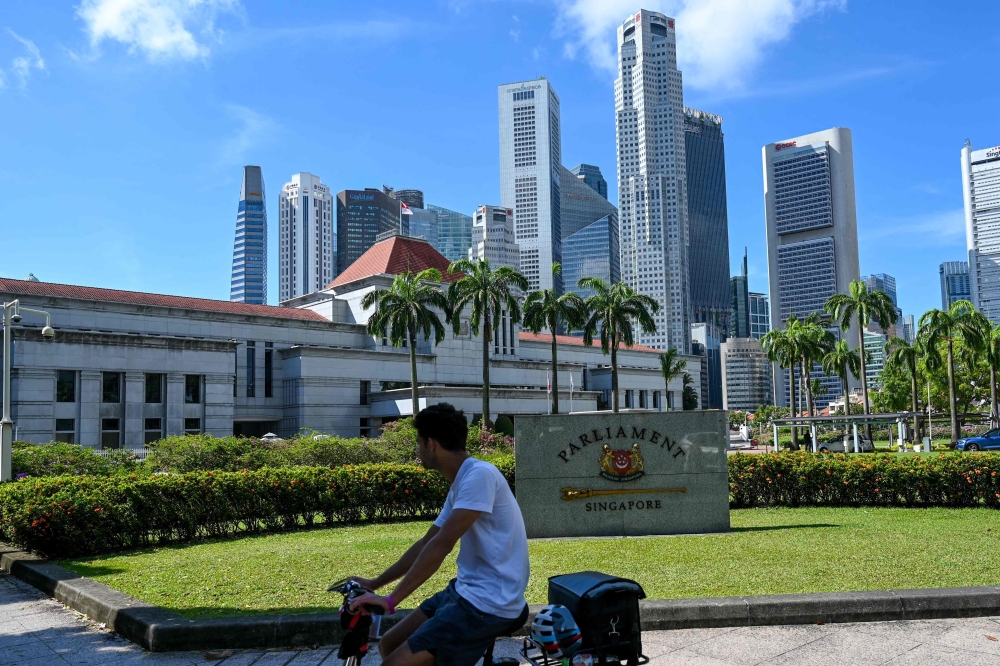 A man rides a bicycle in front of the Parliament House building in Singapore on April 2, 2024. Singapore authorities have warned the public against irresponsible online behaviour ahead of the May 3 general election, cautioning that such actions could be criminal and threaten the electoral process. — AFP pic 