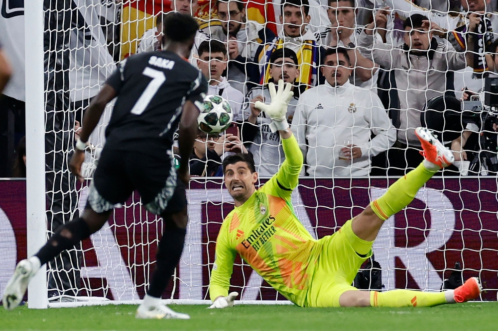Real Madrid's Belgian goalkeeper Thibaut Courtois stops the ball as Arsenal's English midfielder  Bukayo Saka shoots from the penalty spot. — AFP pic