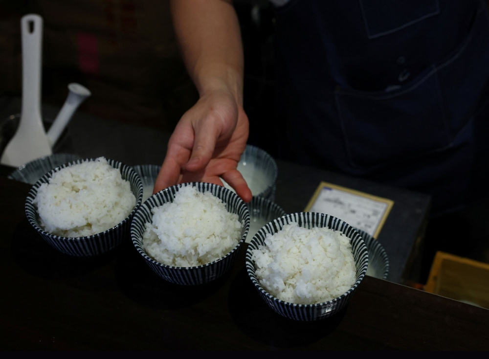 Arata Hirano prepares bowls of cooked California-grown Calrose rice to serve to customers at his restaurant Shokudou Arata in Tokyo April 14, 2025. — Reuters pic 