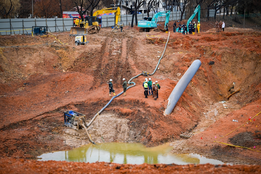 Fire and rescue personnel work to pump out rainwater from the crater at the gas pipeline explosion site in Putra Heights, Subang Jaya, on April 7, 2025. — Bernama pic