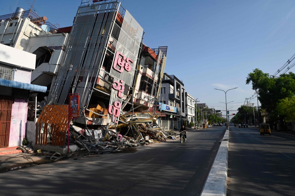 A man on motorcycle rides past a damaged building in Mandalay on April 13, 2025, following the devastating March 28 earthquake. — AFP pic