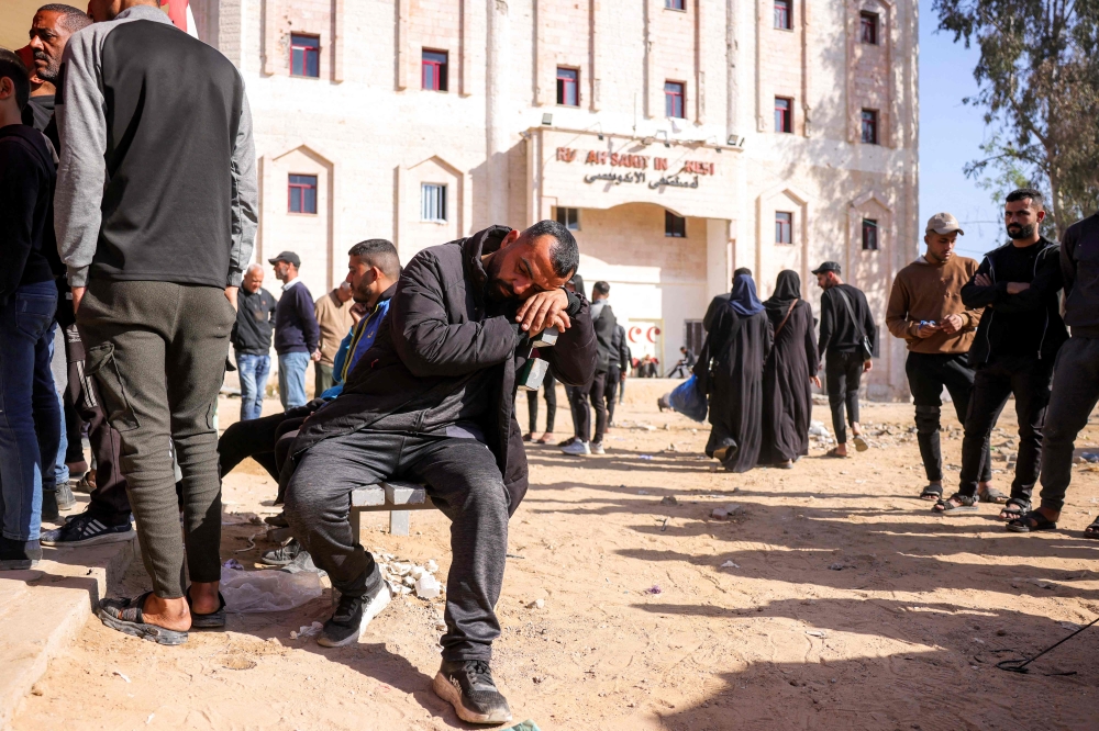 A man rests on a bench as people wait outside the Indonesian Hospital in Beit Lahia in the northern Gaza Strip on April 18, 2025. — AFP pic 