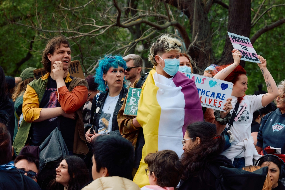 Protesters wave flags and hold placards as they gather in Parliament Square beside the houses of the UK parliament in support of trans rights in London on April 19, 2025. — AFP pic